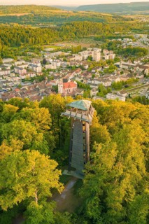 An observation tower rises above a thick forest with a city in the background, Tiengen, Waldshut,