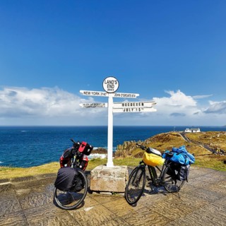 Two e-bikes by the sea, famous signpost to New York, John o' Groats, Scilly and Höxter Bödexen,