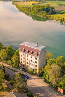 Large building on the riverbank, surrounded by trees and quiet landscape in summer, electrification