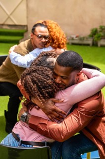 Diverse group in a warm therapy session sharing feelings and embracing for comfort, connection and