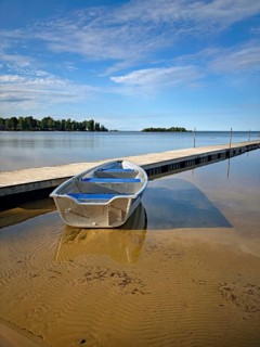 Metal boat on a sandy beach next to a long jetty. Quiet and clear atmosphere, Vänern, Mellerud,