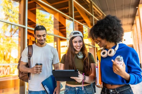 Diverse group of young students walking together on a vibrant university campus, sharing