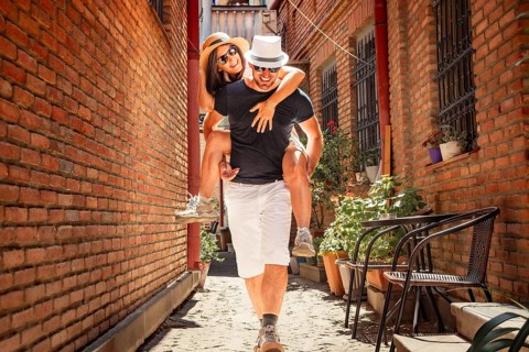 Beautiful young tourist couple Happy caucasian couple having fun piggyback visiting walk narrow