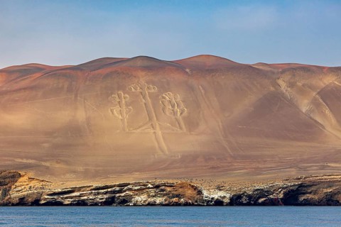 Geoglyph in the shape of a candelabra on sand dunes off a coast, candelabra of Paracas in Peru