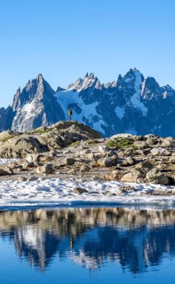Young man in front of impressive mountain landscape in morning light, reflection in the Lac Blanc