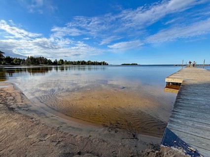 Jetty on a sandy beach with clear water and blue skies. Quiet summer atmosphere, Vänern, Mellerud,
