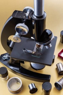 Vintage black Bausch & Lomb research microscope with box of glass slides and objectives on light