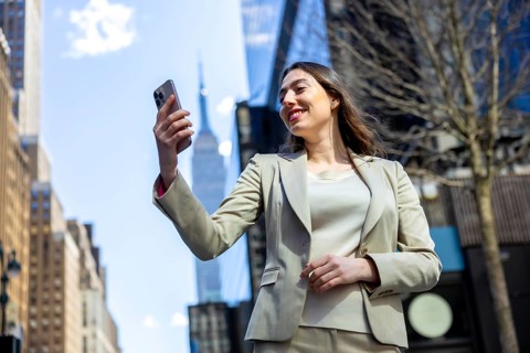 Businesswoman posing for a self portrait on her mobile phone, reflecting concepts of urban tourism,