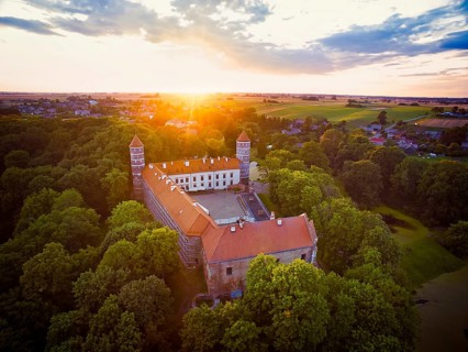 Historical Panemune castle in dramatic sunset conditions with green nature and sunset flare.