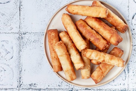 Fried spring rolls with cheese, on a plate, with cream sauce, no people