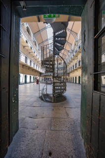 Narrow view of a spiral staircase in a bright prison corridor with old-fashioned design, Kilmainham