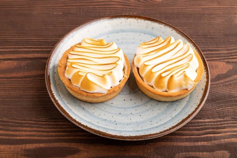 French lemon tart with meringue on brown wooden background, side view, close up