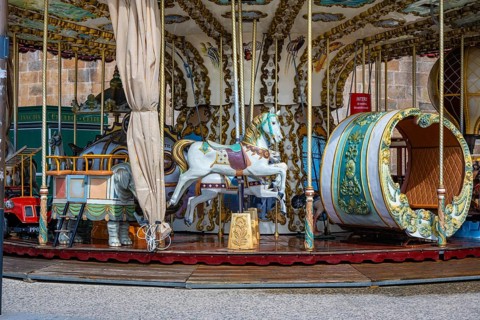 Nostalgic horse carousel at a fair with ornately decorated white carousel horses and a decorative