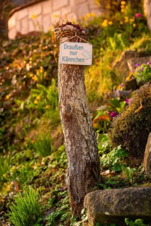 Wooden post with sign in a green, blooming garden, Dachtel, Aidlingen, Heckengäu Region, Germany