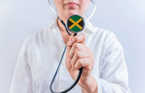 Female doctor holding stethoscope with Jamaica flag. National health system of Jamaica