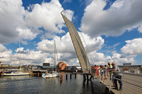 Klappbrücke über einem Hafen unter einem bewölkten Himmel mit Menschen, die auf einer Brücke