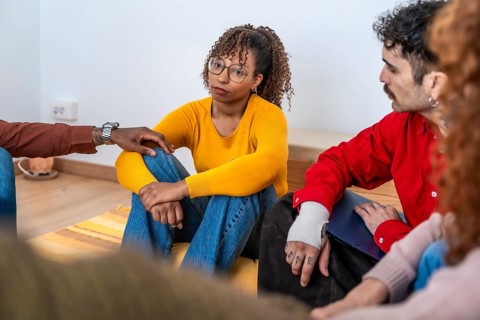 Diverse people sitting on the floor in a circle, sharing experiences and finding comfort during a