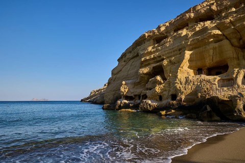 Neolithic caves, former hippie paradise, rocky coastline with caves and calm waves on a sunny day,
