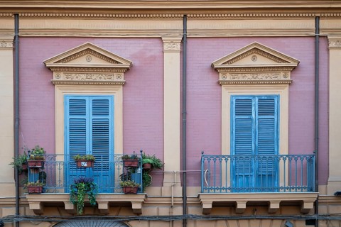 View of a purple neoclassical façade with two blue-painted balconies and shutters, Palermo, Sicily,
