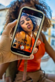 Hand holding a smartphone displaying a smiling young woman making a kissing face for a selfie,