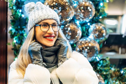 Young woman in winter clothing with festive decorations. A person in a white puffer jacket, gray