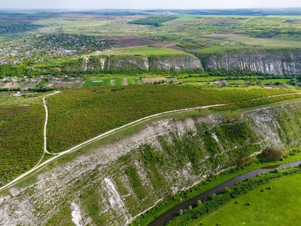 Aerial view of a river snaking through hilly and green fields near a village, aerial view,