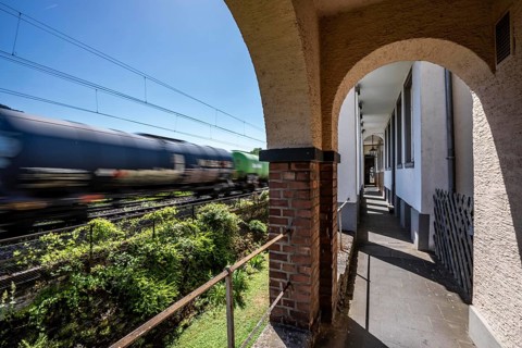 Freight train passing through town in Bacharach, right by the residential buildings, front gardens