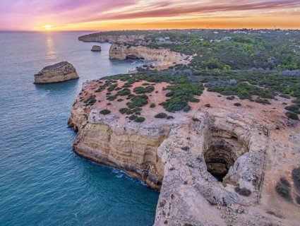 Drone sunset view of Arco de Albandeira at Praia de Albandeira in Algarve, Portugal, with limestone