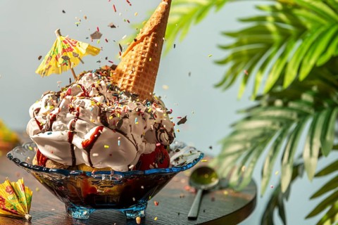 Sprinkles fall on sundaes decorated with cream, ice cream cone, umbrella and chocolate