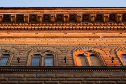 Façade of Palazzo Strozzi with intricately crafted roof cornice, warm evening light, old town,