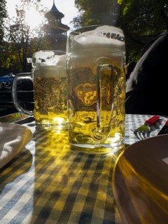 Full beer mugs on a set beer garden table in front of the Chinese Tower, English Garden, Munich,