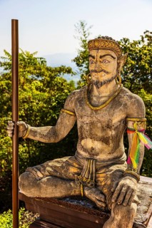 Stone statue of a seated temple guard in the Wat Phra That Don Phra Chan Buddhist temple, near