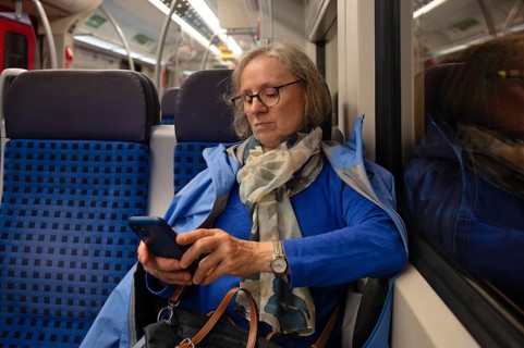 Interior view, elderly woman, glasses, sitting in S-Bahn, subway, train, typing on smartphone, cell