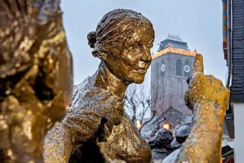 Bronze statue of people, in the background a historic tower in a wintery atmosphere, The