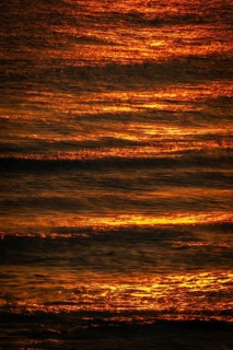 Setting sun bathes the sea and small waves in golden light, long exposure, Houvig Beach, North Sea,