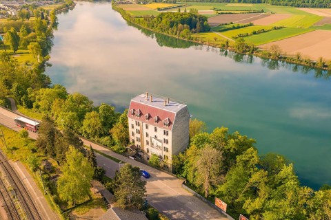 River building with surrounding landscape, green fields and trees in summer weather,