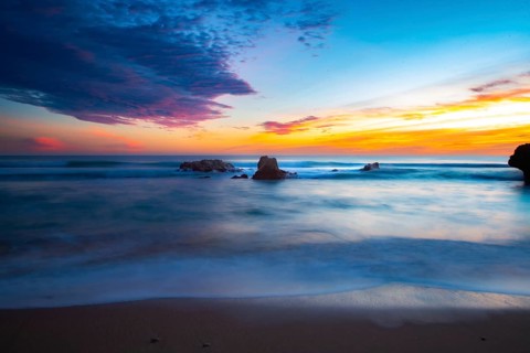 Peaceful sunrise by the sea with smooth waves and glowing sky, sunset, Praia do Amado,