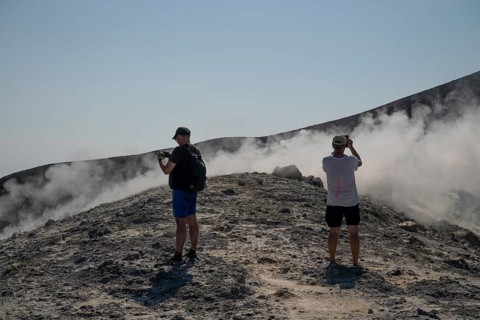 Tourists stand at the crater rim and photograph rising sulfur clouds, Vulcano, Aeolian or Lipari