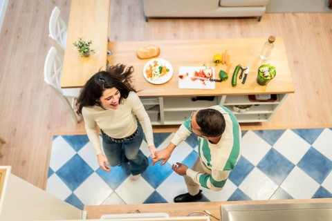 Joyful couple holding hands and dancing together in their home kitchen, sharing a loving and fun