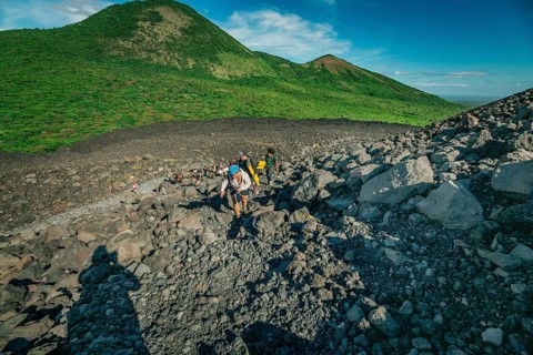 Group of tourists ascends the trail of the Cerro Negro volcano, surrounded by vegetation, León,