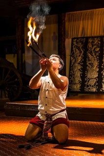 Young Thai man in traditional clothing in a historic show with burning torches, Old Chiang Mai