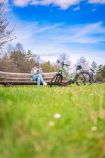 Person on a bench with bicycle in natural environment, blue sky with clouds, e-bike, Gechingen,