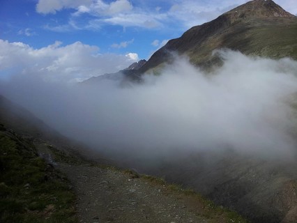 A hiking trail leads along a foggy mountain landscape, E5, hiking in the Alps, crossing the Alps,