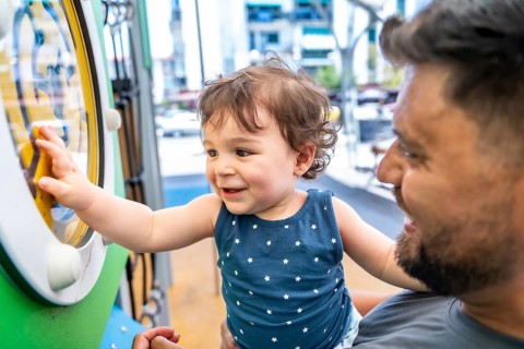 Father holding his happy toddler son, enjoying playtime and interacting with a colorful toy on the