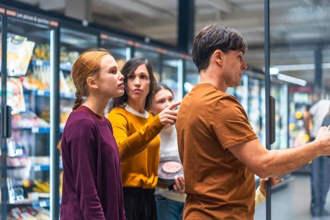 Family comparing products and making decisions together in the frozen food aisle of a supermarket,