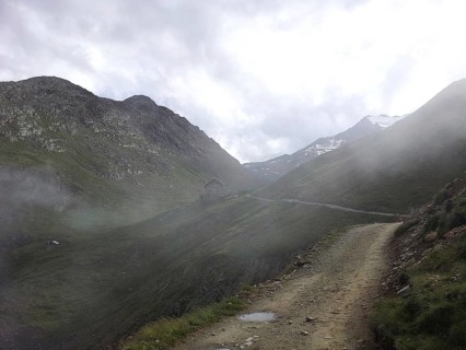 A narrow path winds through a foggy mountain landscape, E5, hiking in the Alps, crossing the Alps,