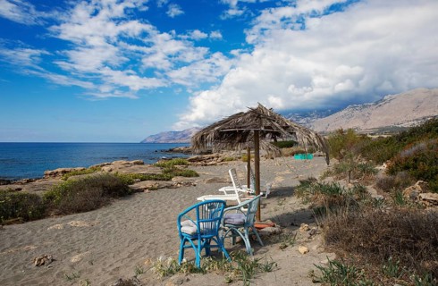 Colourful chairs and weathered umbrellas on the beach in Frangokastello on the Libyan Sea, in the