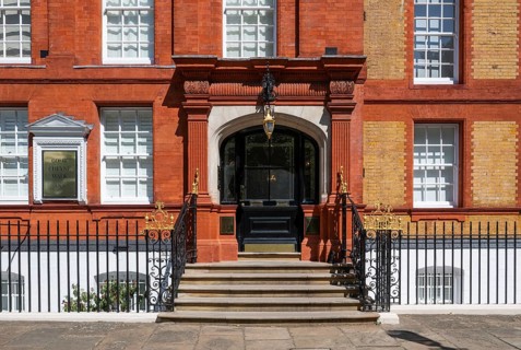 Elegant building with brick staircase, decorative elements and a large black entrance door,