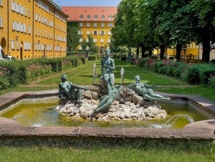 Yellow residential buildings, courtyard, bronze figures on rocks in the well, borstei,