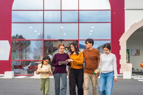 Family walking together outside a supermarket, father and mother with their three daughters